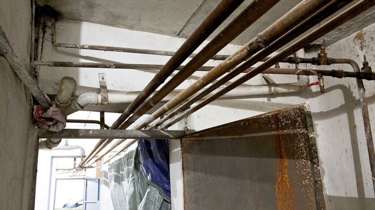Old metal supply pipes running across a basement ceiling