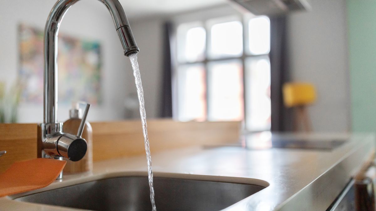 Kitchen tap running a steady stream into a stainless steel sink