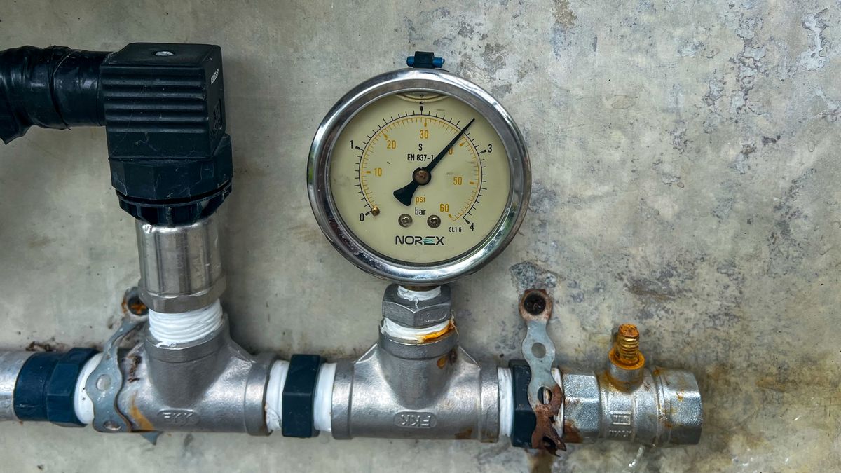 Pressure gauge on metal pipework, its dial marked in both psi and bar