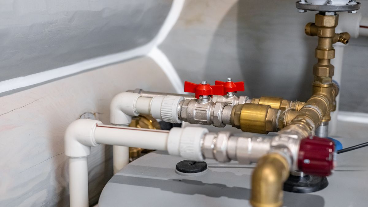 Top of a storage water heater with red-handled isolating valves on the inlet and outlet